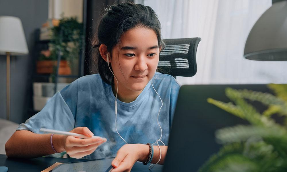 child looking at laptop while doing homework