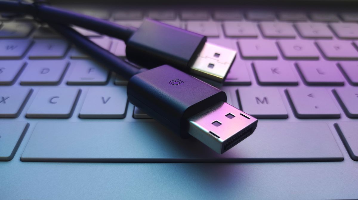 A pair of DisplayPort cable connectors laid across a laptop keyboard.